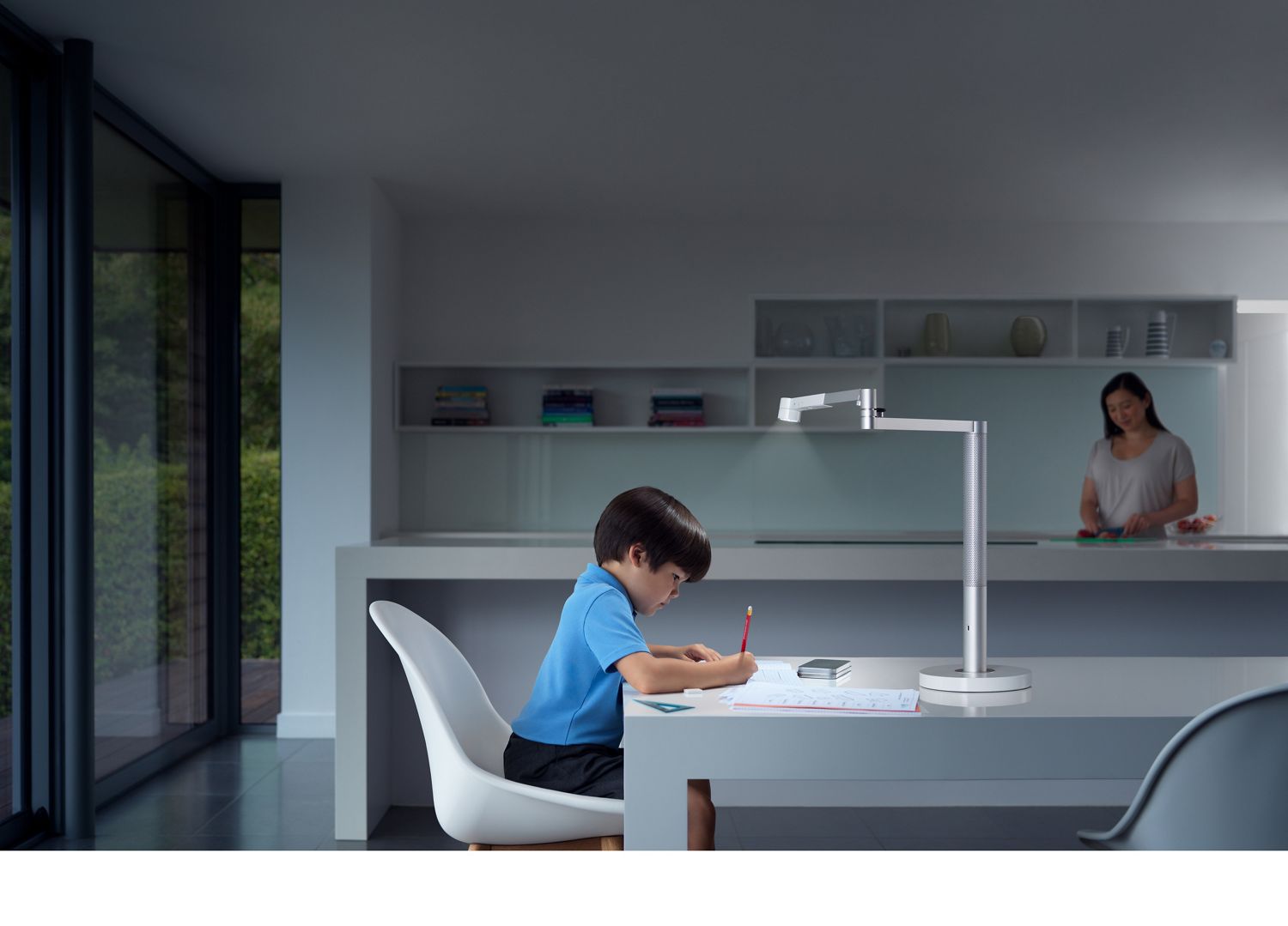 Un garçon étudie sous une lampe de bureau puissante